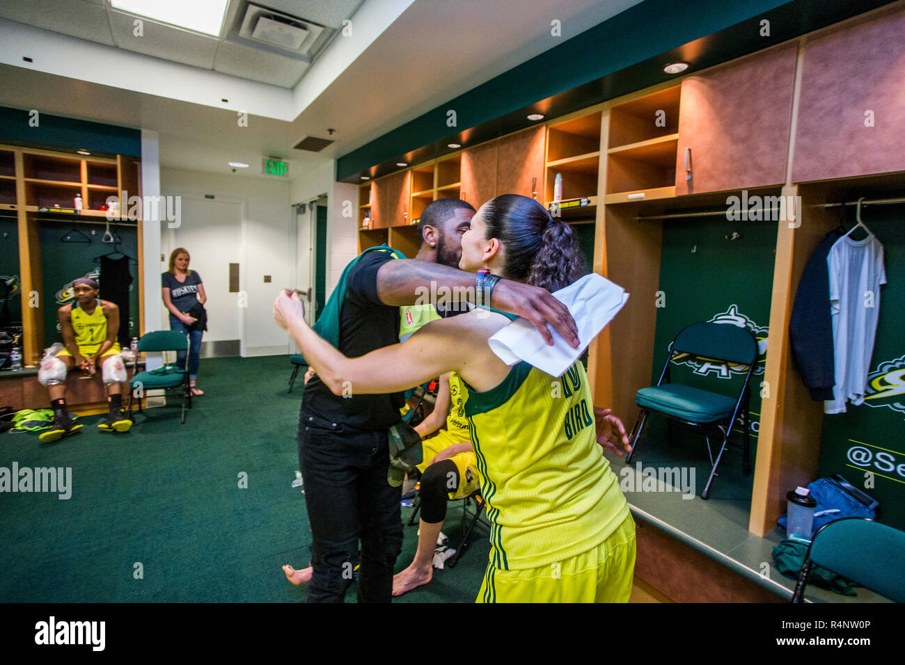 Male and female basketball players embracing in locker room, Seattle, Washington State, USA Stock Photo