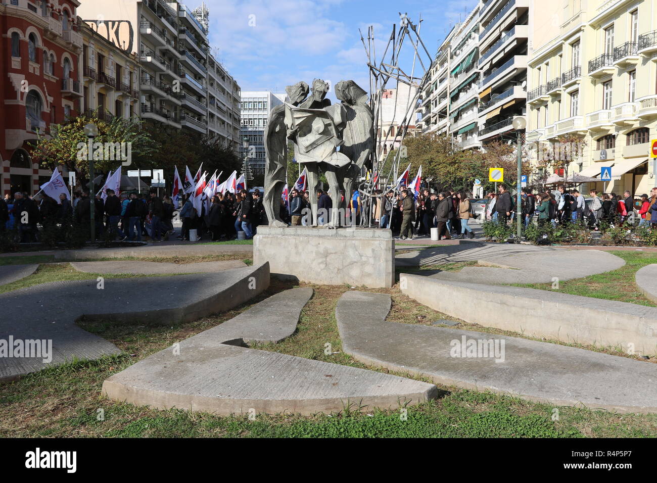 Thessaloniki, Greece, 28th November, 2018. Protesters from the communist-affiliated trade union PAME walk past a statue during a 24-hour walkout staged by Greece's largest private sector union GSEE  against planned pension cuts and to demand the reversal of labour reforms implemented under the country's third bailout. The strike by the GSEE union is the second major strike since Greece exited its bailout programm in August. Credit : Orhan Tsolak / Alamy Live News. Stock Photo