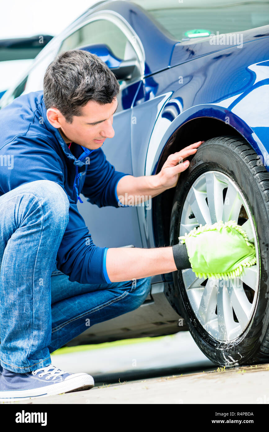 Worker using microfiber car wash mitt for cleaning rim Stock Photo