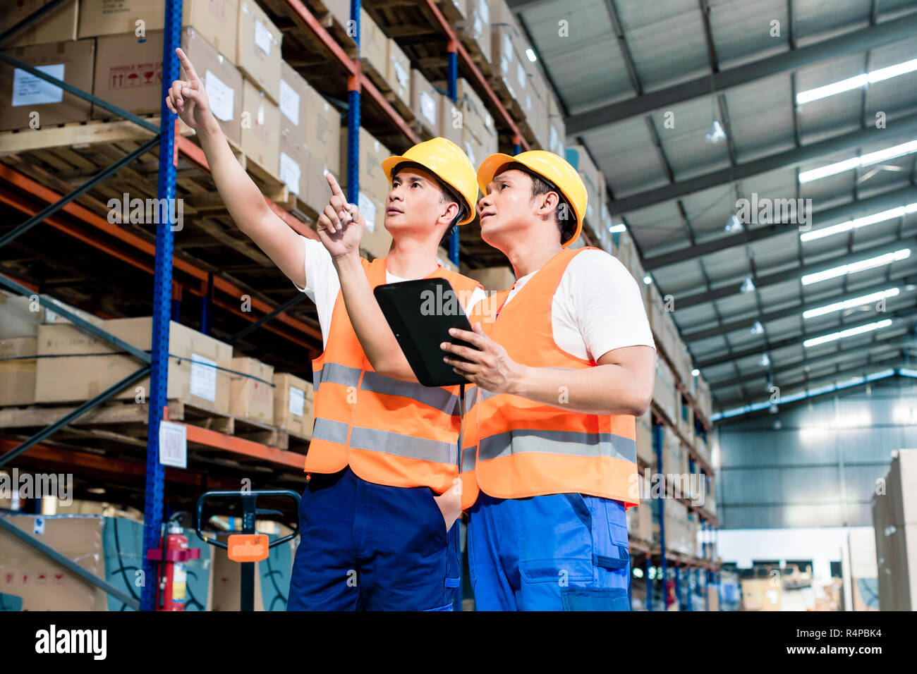 workers-in-logistics-warehouse-at-forklift-checking-list-stock-photo