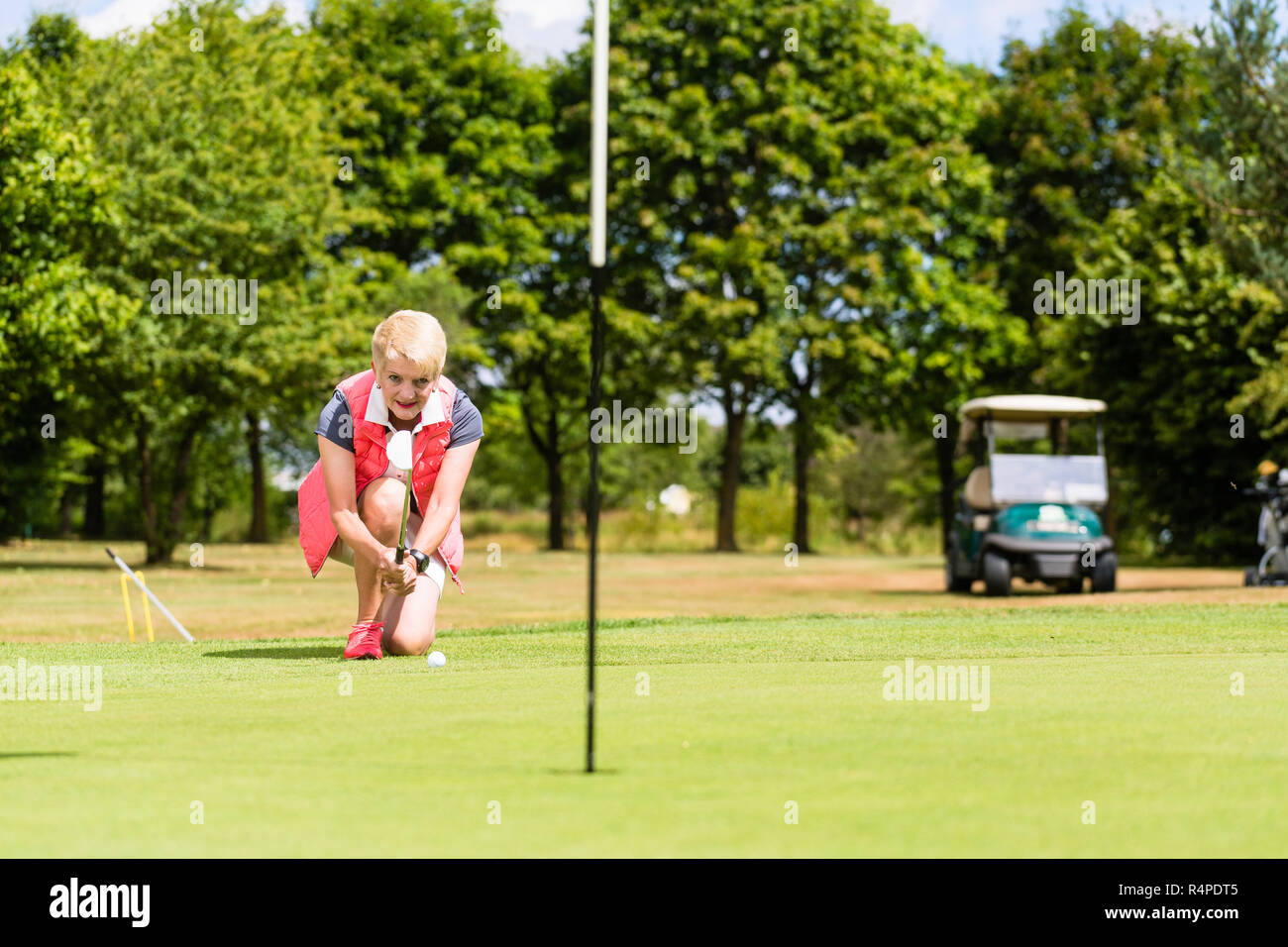 Senior golf player aiming his stroke to the hole Stock Photo