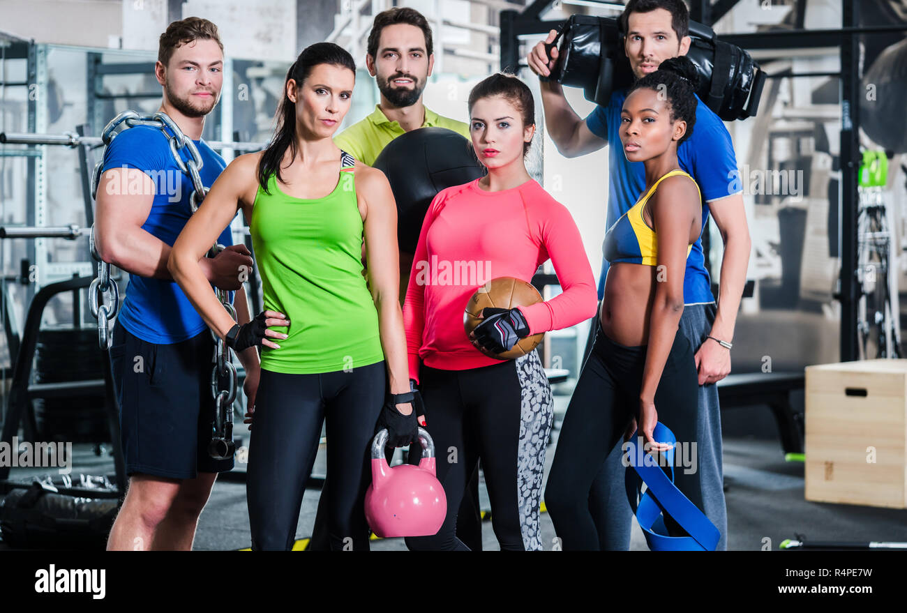 Group of women and men in gym posing at fitness training Stock