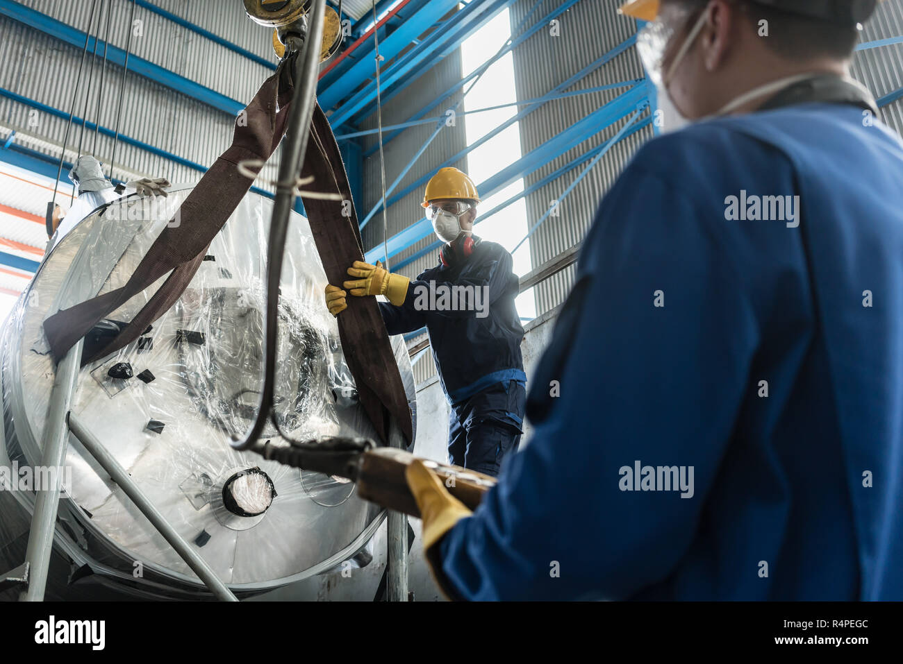 Workers handling equipment for lifting industrial boilers Stock Photo