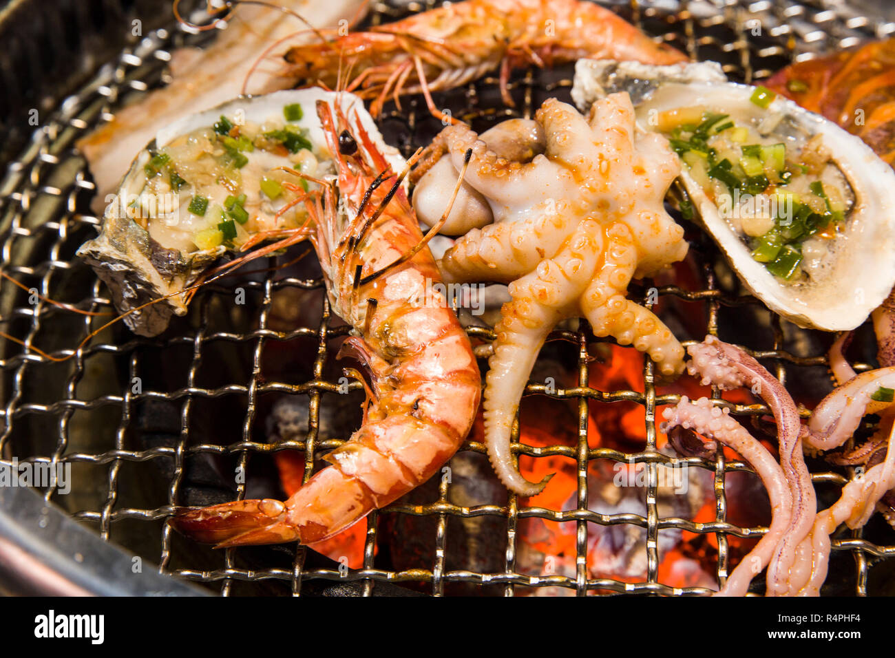 Grilling seafood of shrimp, octopus and oysters on hot charcoal Stock