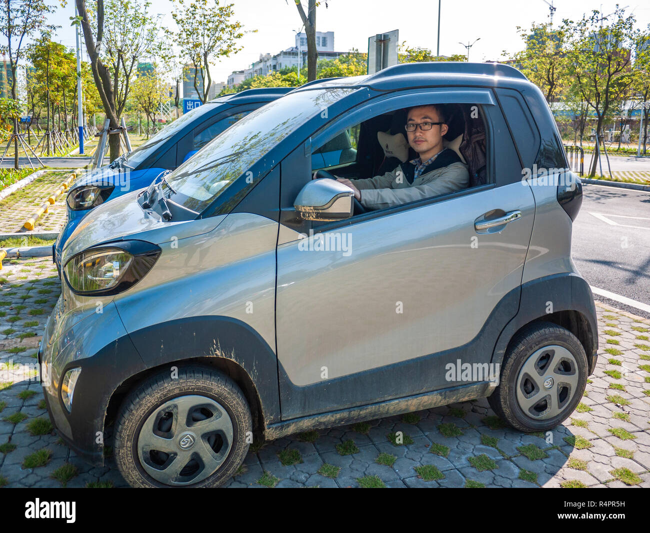 Man sitting on driver seat of a Baojun E100 -- a two-seater electric car. The car is affordable and non-polluting. Stock Photo