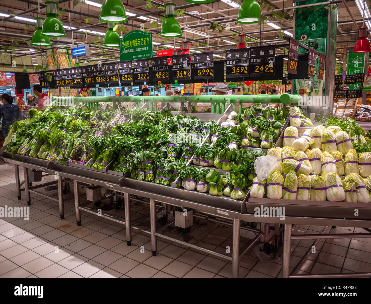 A variety of fresh green leafy vegetables displayed in a supermarket with price tag on top for customers to choose. Liuzhou, China. Stock Photo