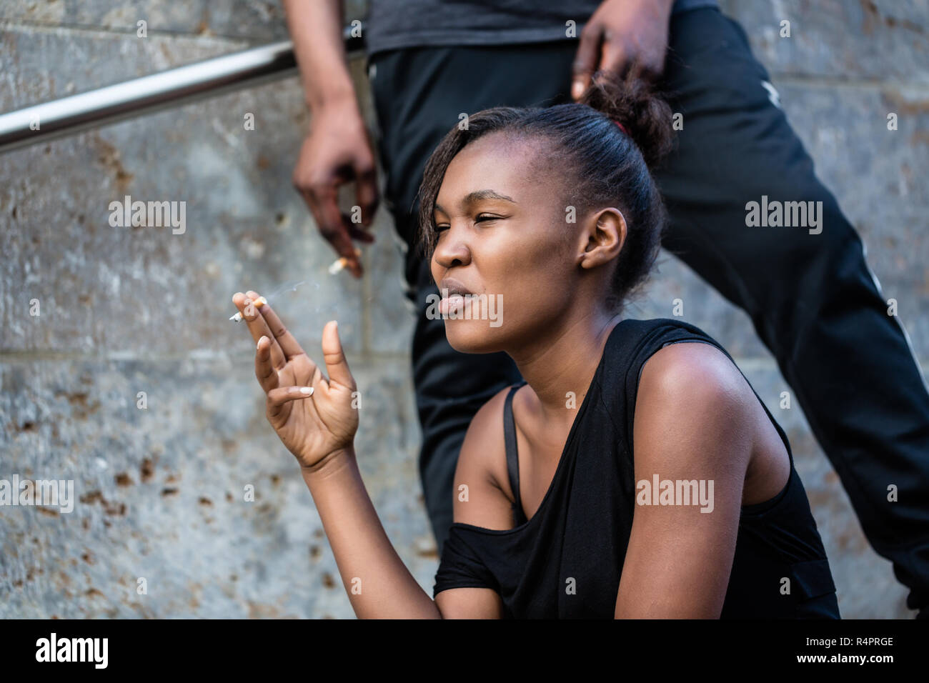 Young African American woman and man smoking outdoors in the city Stock Photo