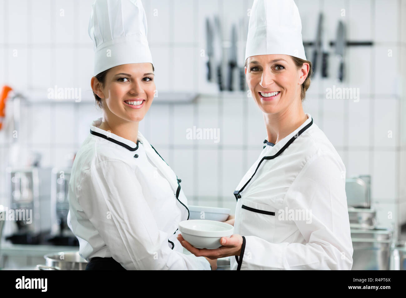female chefs in commercial kitchen wearing white uniforms Stock Photo