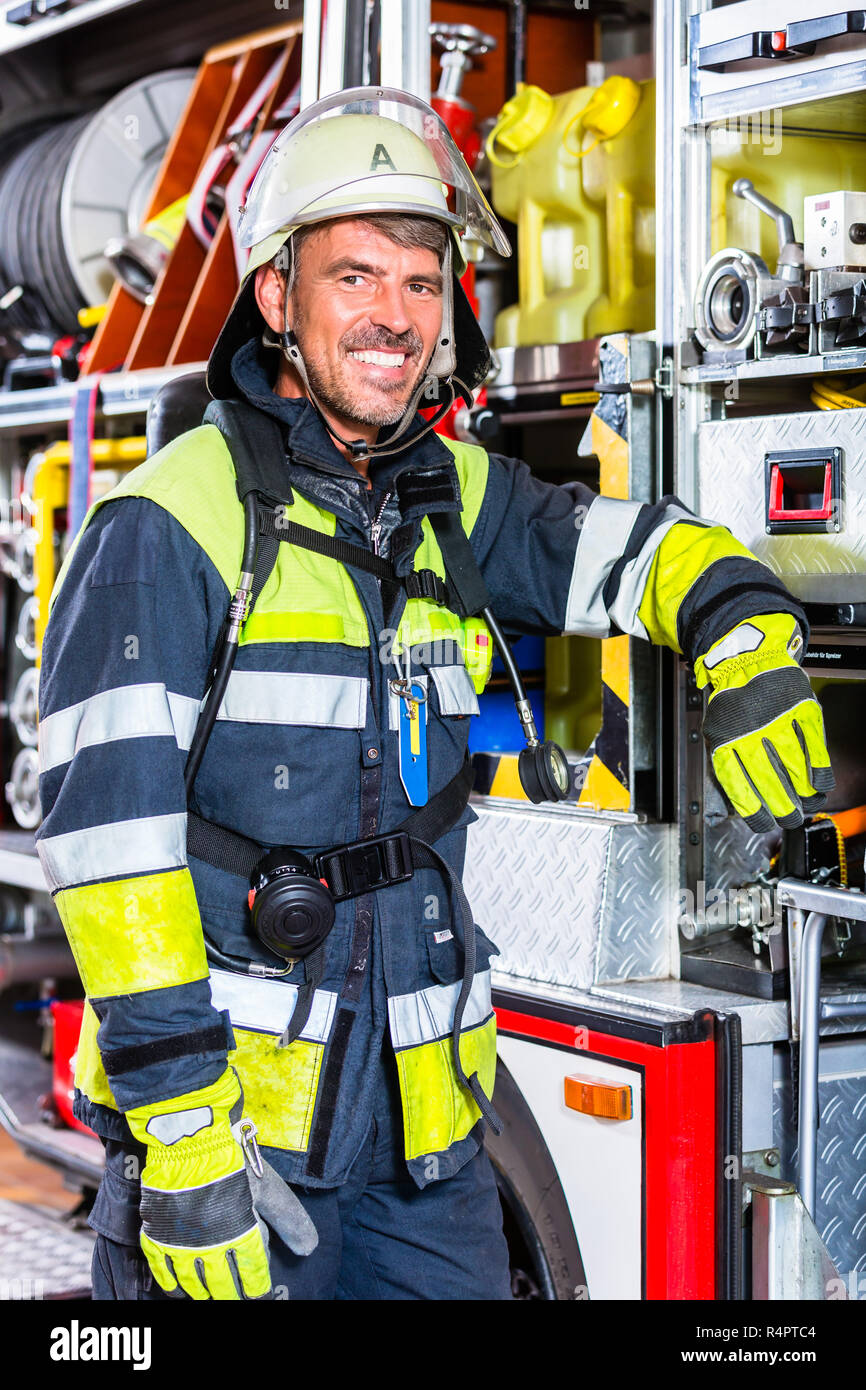 Fire fighter in protective clothes leaning at fire engine Stock Photo