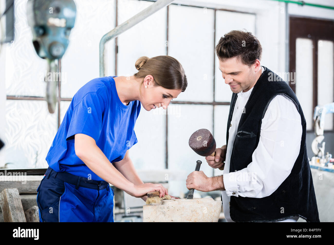 two Stonemasons carving pillar out of stone in workshop Stock Photo