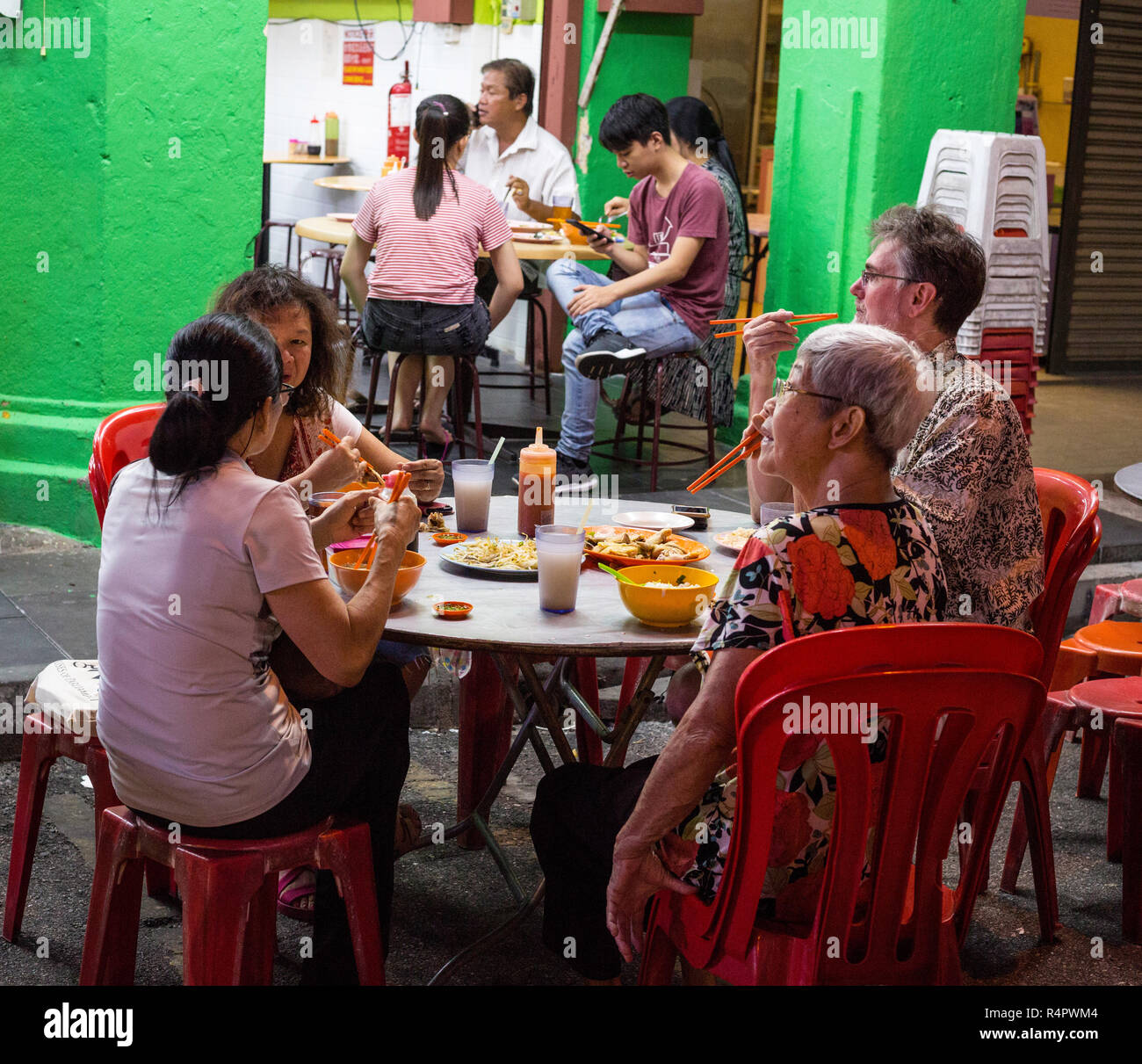 Family Having Dinner at Sidewalk Restaurant at Night, Ipoh, Malaysia. Stock Photo