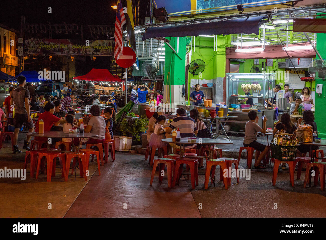 Families Dining Outdoors at Night at a Sidewalk Cafe, Ipoh, Malaysia. Stock Photo