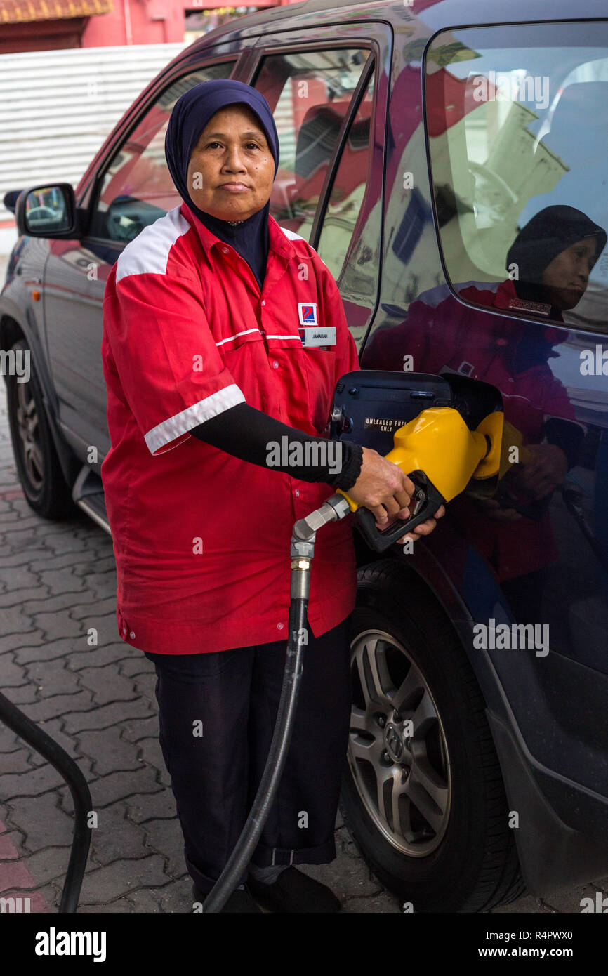 Muslim Female Gas Station Attendant Pumping Gas, Ipoh, Malaysia. Stock Photo
