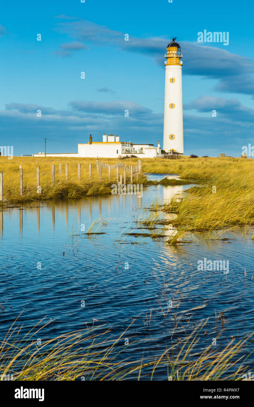Barns Ness lighthouse, East Lothian, Scotland. The building is partly reflected in a flooded area of grassland. Stock Photo