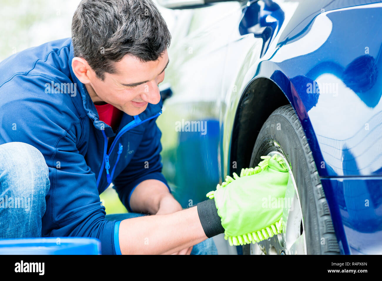 Worker using microfiber car wash mitt for cleaning rim Stock Photo