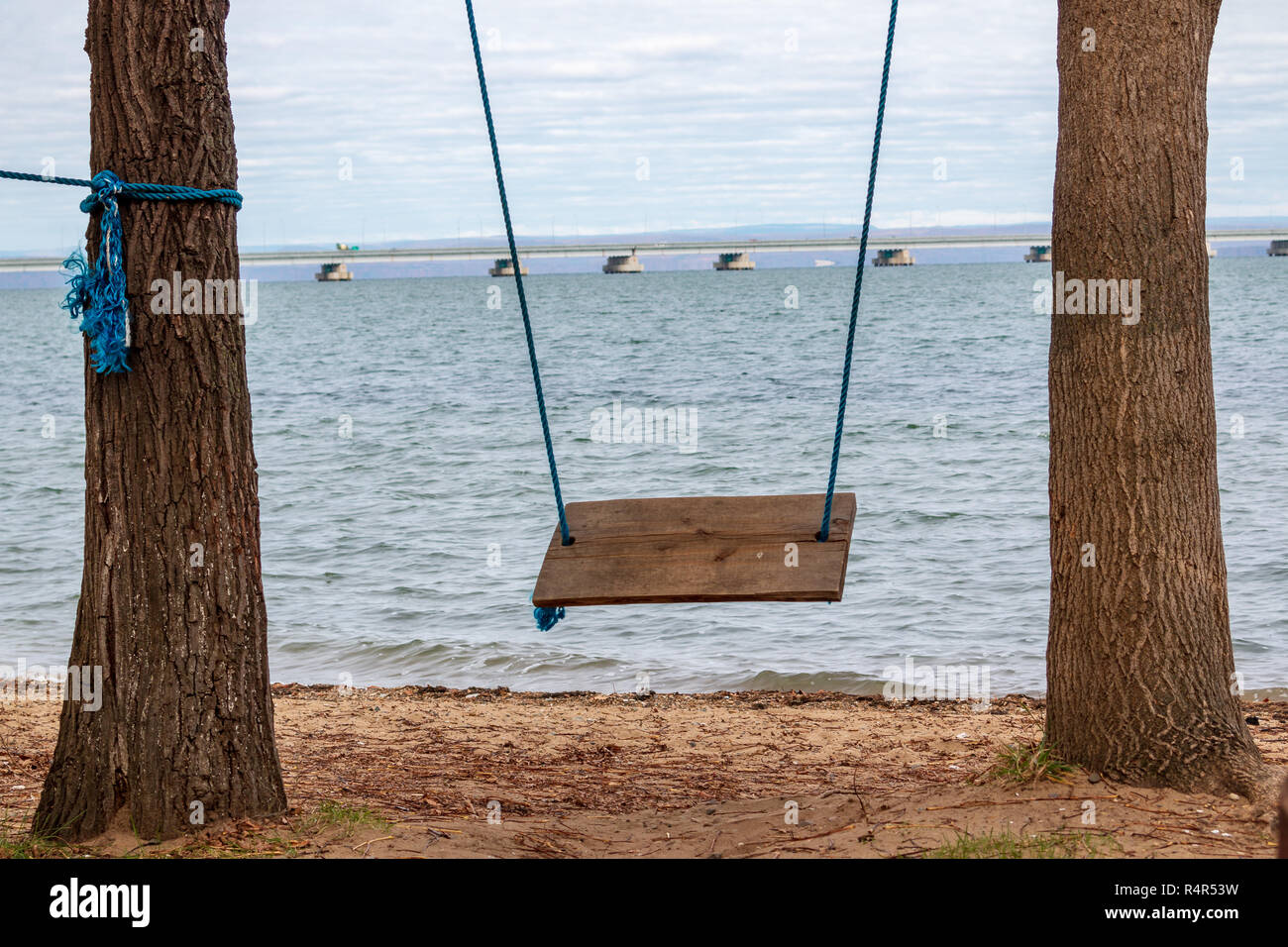 Swing in a recreation park and a view from the shore at Low water bridge from Sedanka to the De Friz peninsula across the Amur Bay of Primorsky Krai R Stock Photo