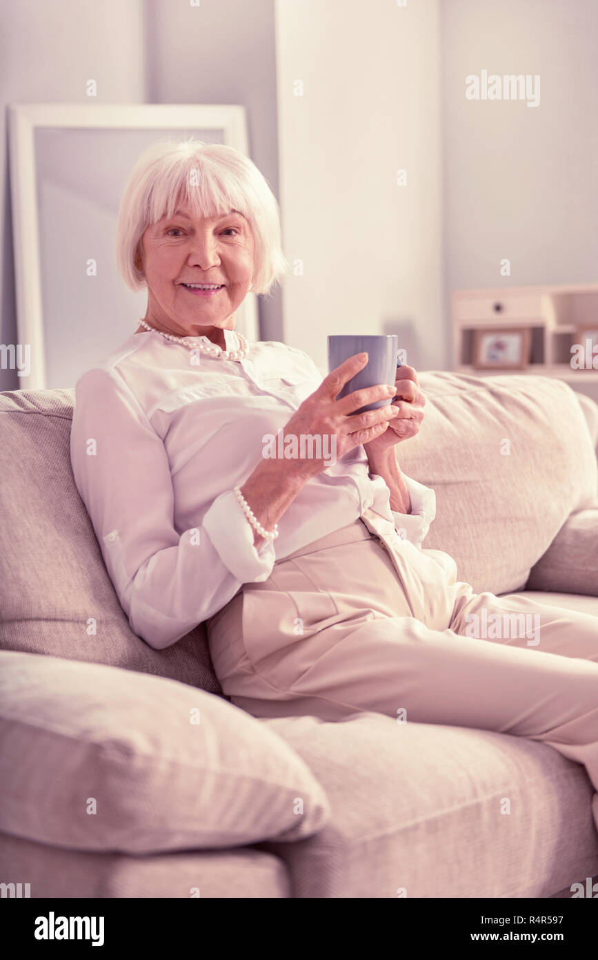 Smiling old lady sitting with cup of coffee Stock Photo