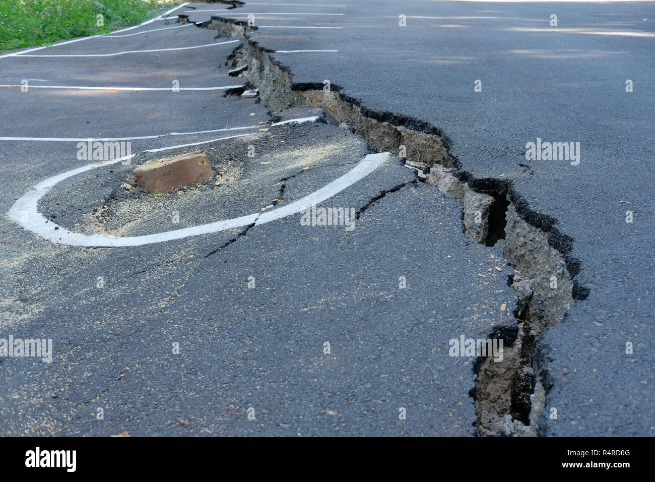 cracks on asphault rural road. damaged collapsed street Stock Photo