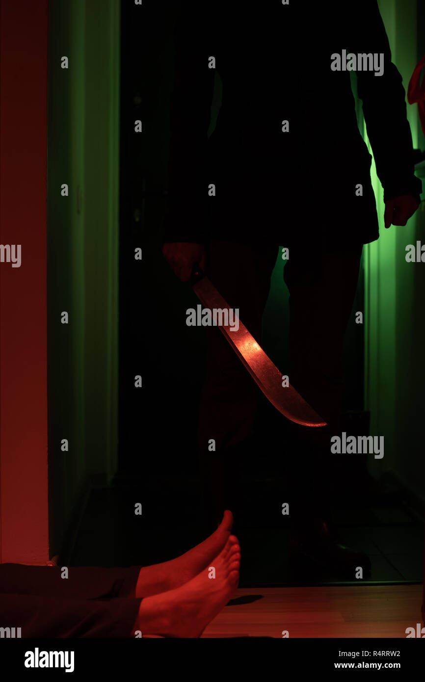 Photo of thief with machete and man lying on floor in dark apartment at