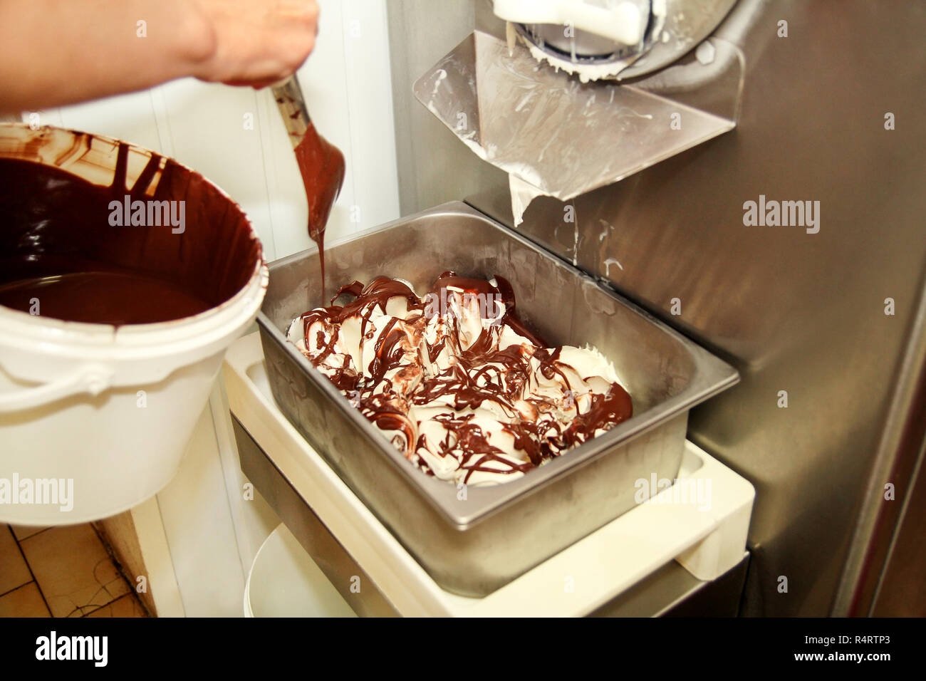 Woman working at ice cream factory is decorations of creamy vanilla ice