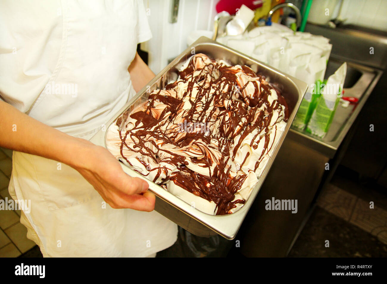 Female worker is working at ice cream factory is carrying creamy