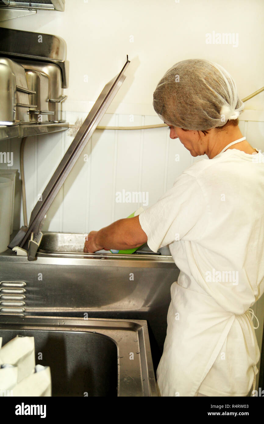 Female chef and worker is working at ice cream factory is pouring