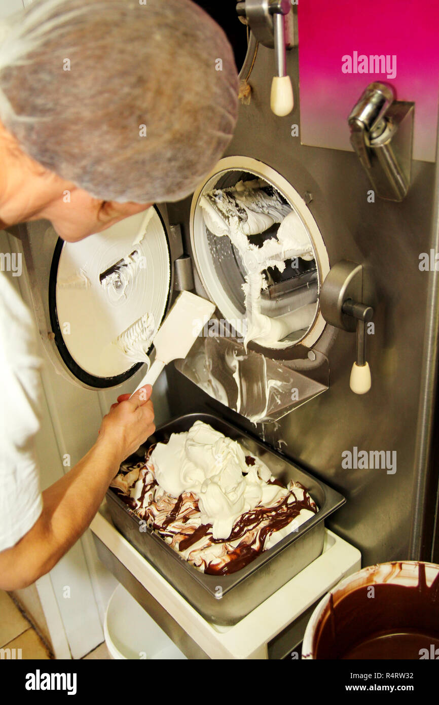 Female chef and worker is working at ice cream factory is cleaning ice