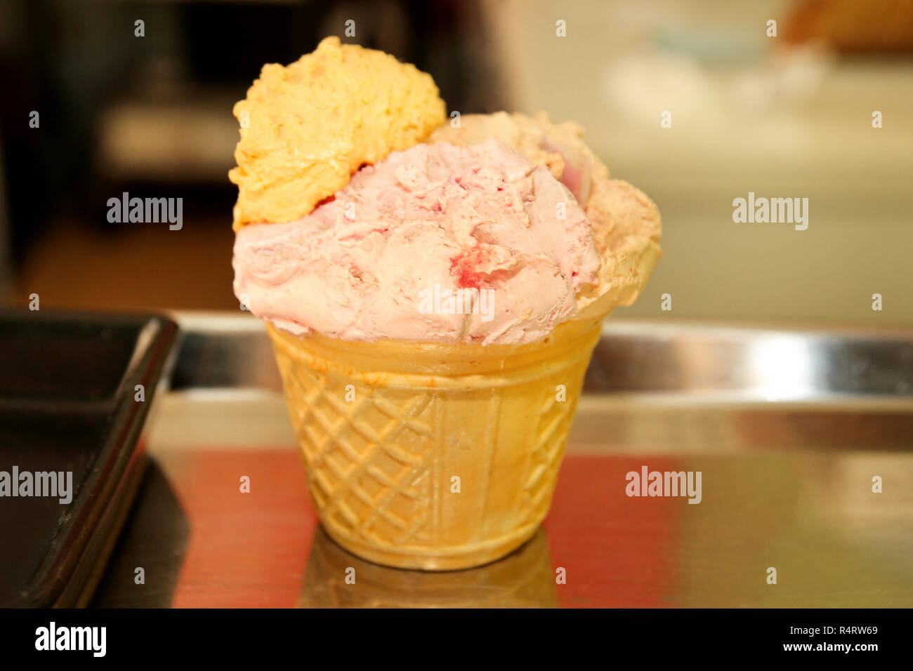 Ice cream in a waffle cup. Scoop of strawberry and lemon ice cream in a ...