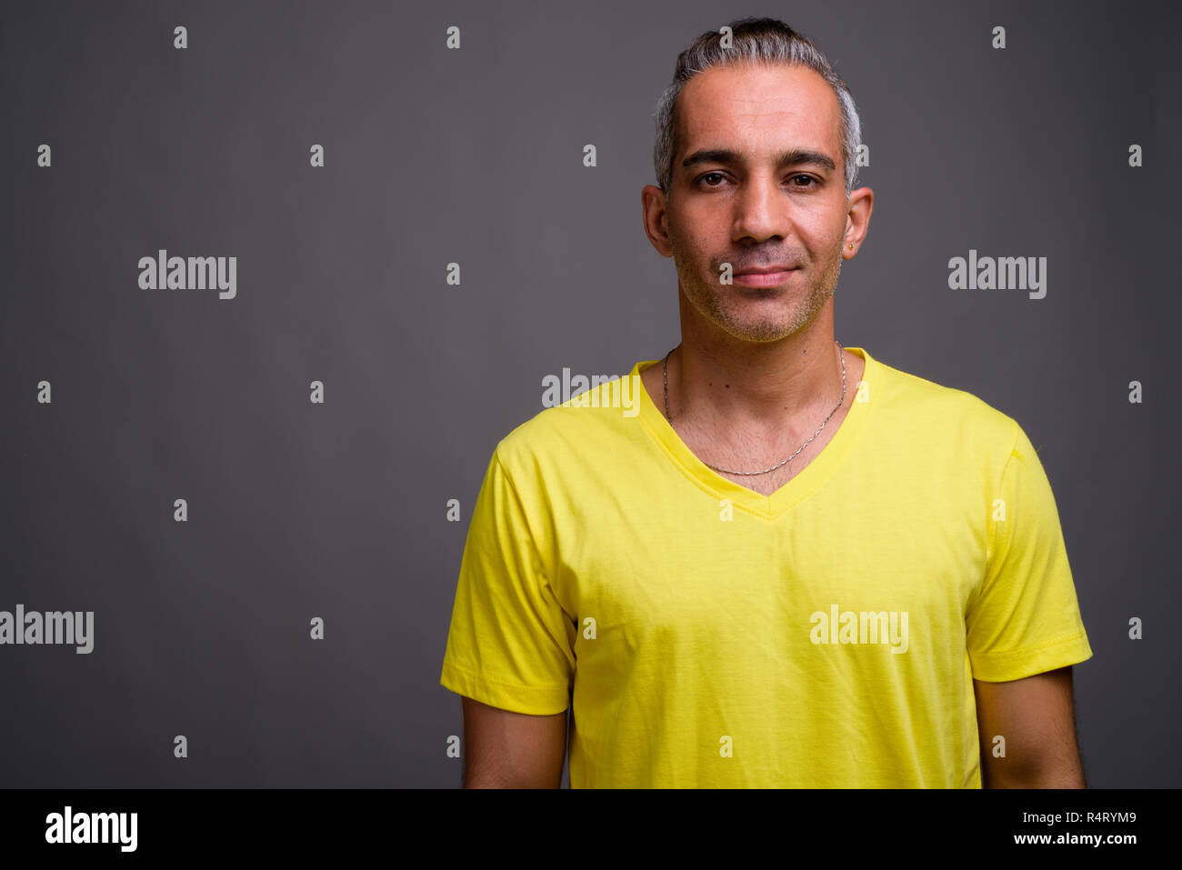 Handsome Persian man with gray hair wearing yellow t-shirt Stock Photo