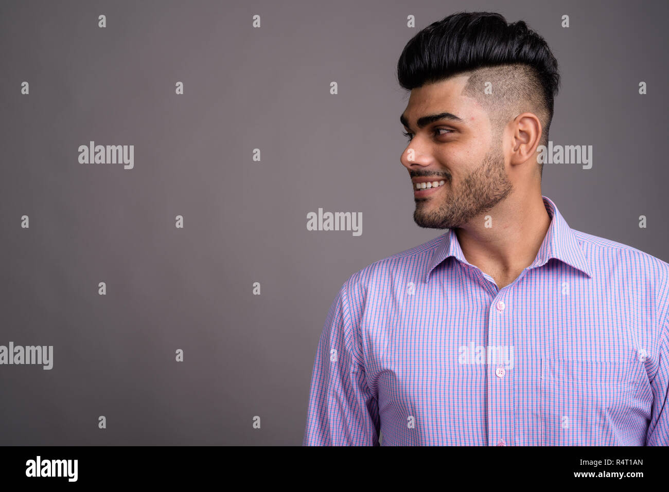 Young handsome Indian businessman against gray background Stock Photo