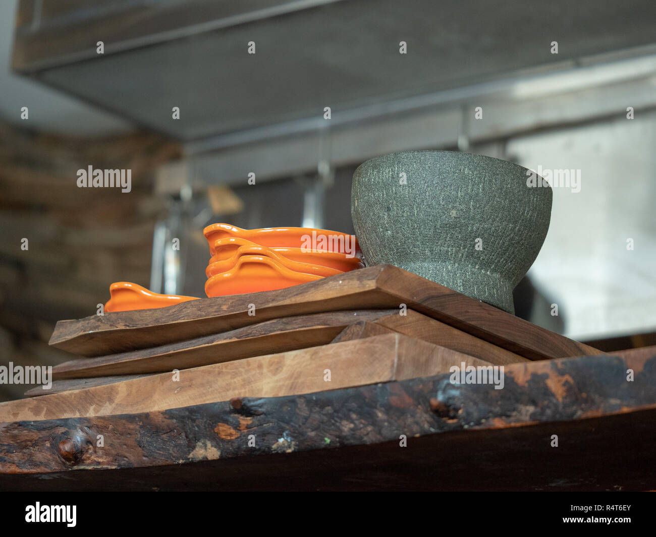 Orange bowls and gray mortar and pestle sitting on a wooden restaurant serving counter Stock Photo