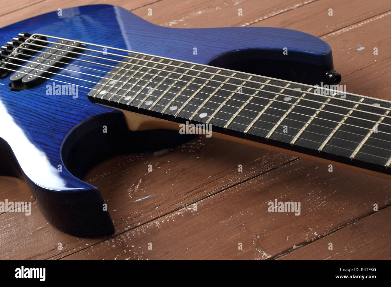 Musical instrument - Fragment 8-string blue electric guitar solid-body on a wood background Stock Photo