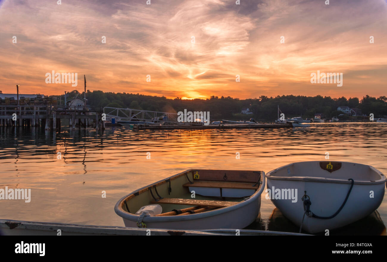 Early morning summer sunrise over calm water and john boats near a working lobster wharf in