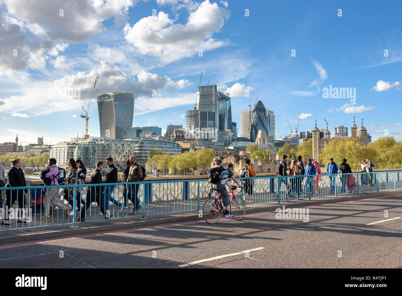 London, UK - April 26, 2018: People cross the Tower Bridge with skyline of London City in the background Stock Photo