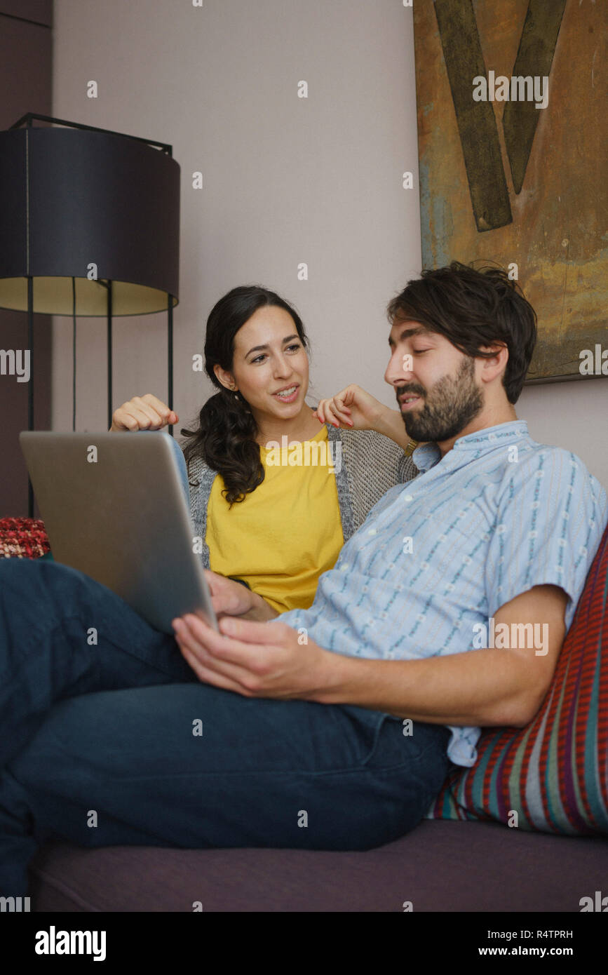 Couple using digital tablet on living room sofa Stock Photo