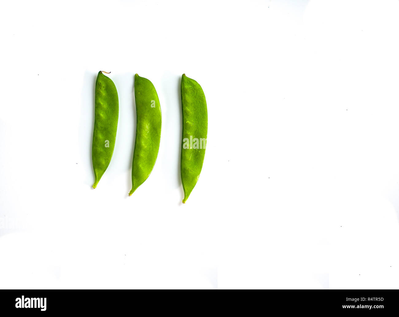 Three snap pea pods on a minimalist white background Stock Photo