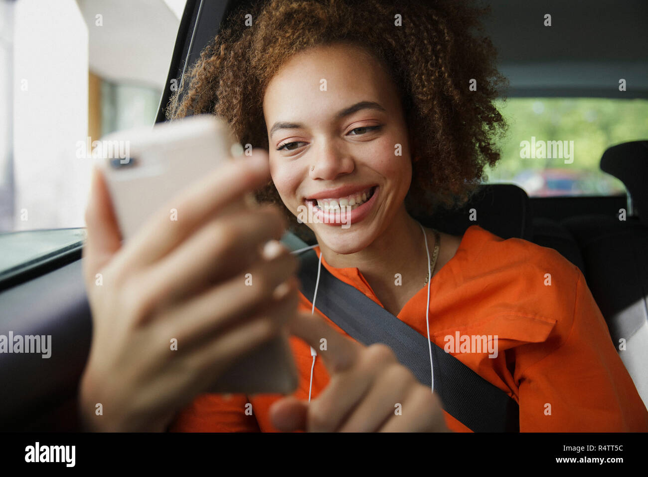 Smiling young woman using smart phone in car Stock Photo
