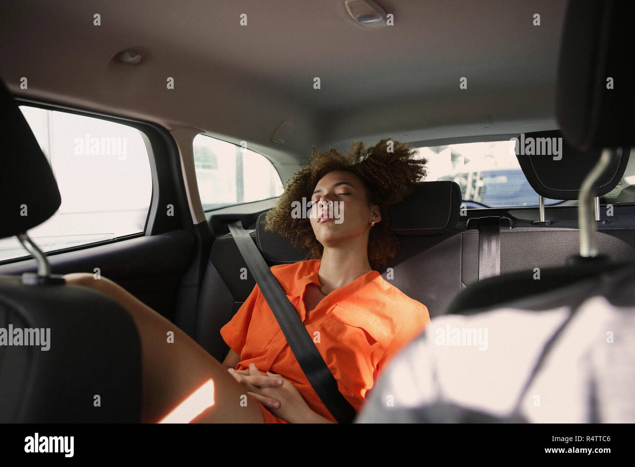Tired young woman sleeping in back seat of car Stock Photo