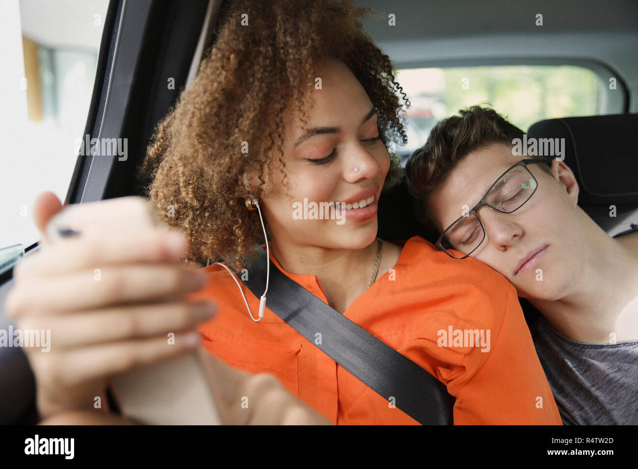 Young couple sleeping and listening to music in car Stock Photo