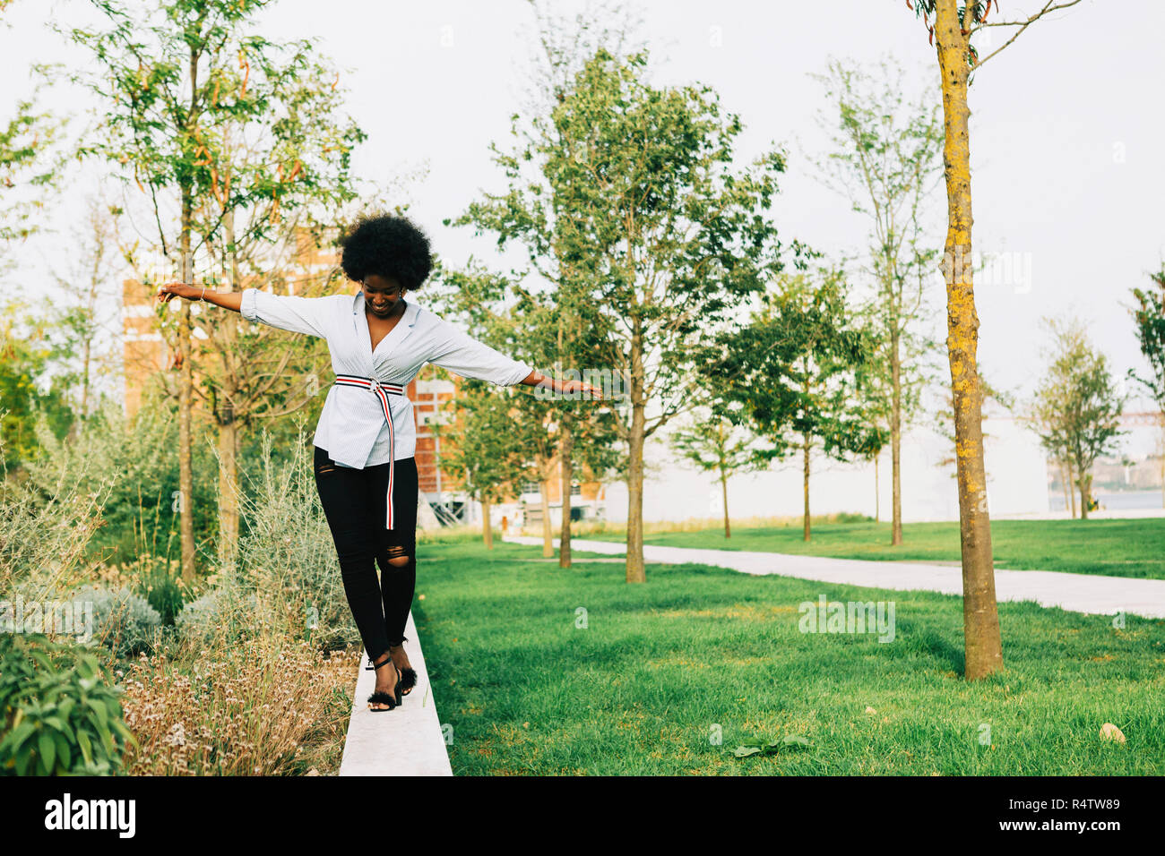 Young woman balancing on ledge in park Stock Photo