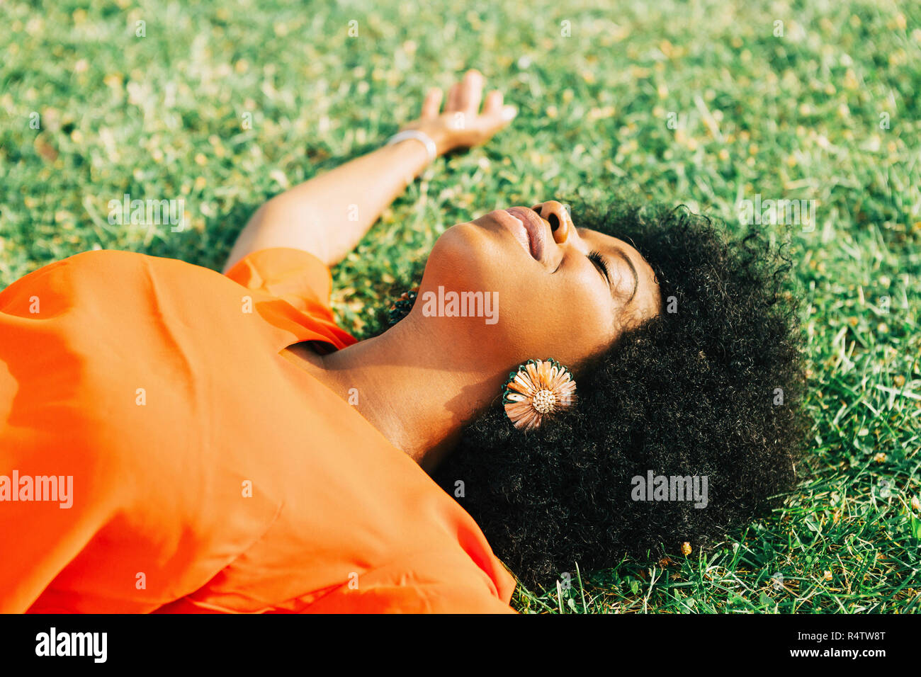 Carefree, serene young woman laying in sunny grass Stock Photo