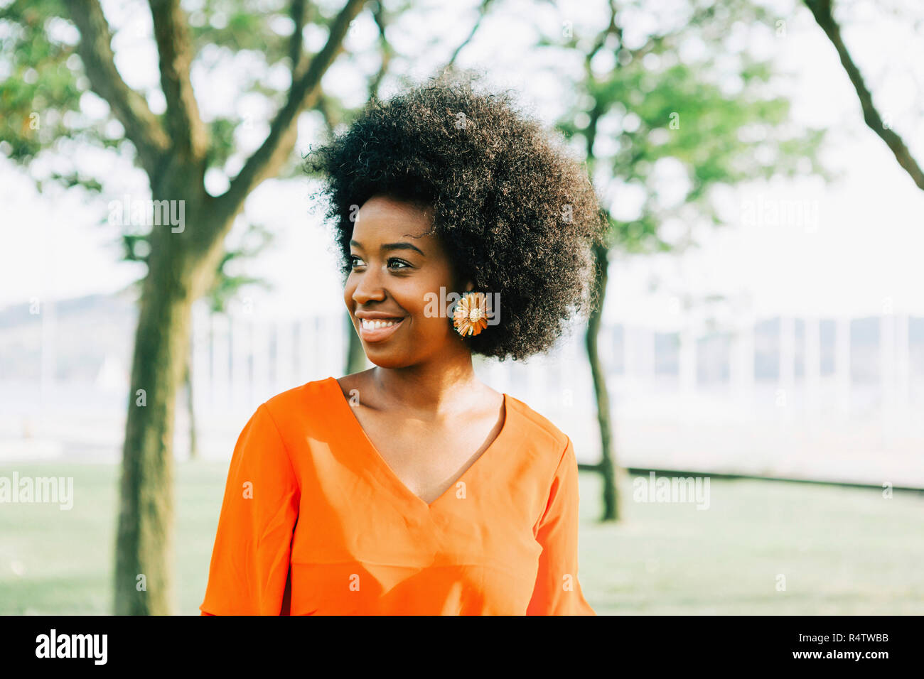 Confident, smiling young woman in sunny park Stock Photo