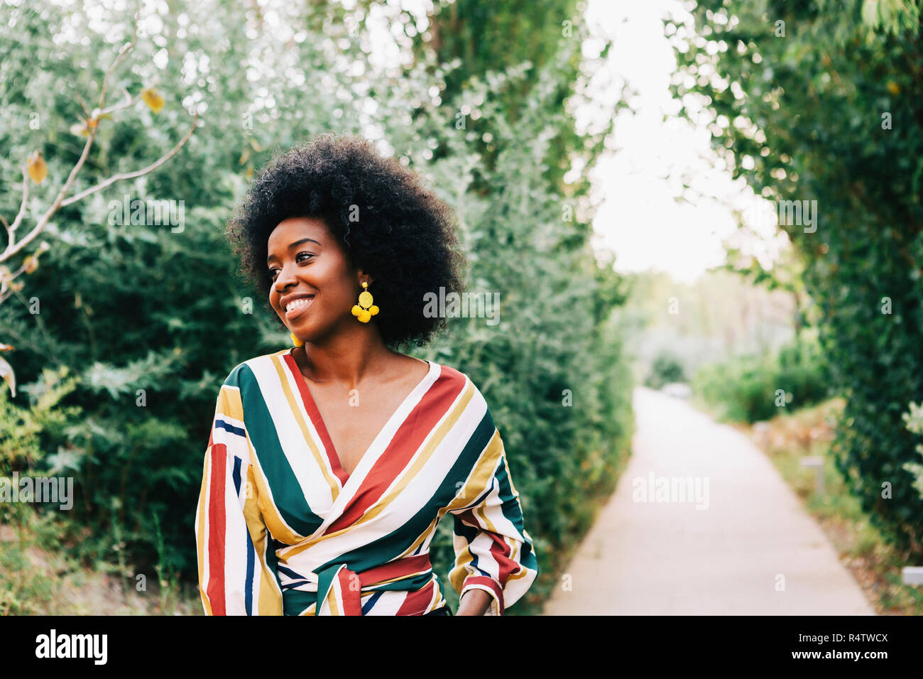Confident young woman on path in park Stock Photo