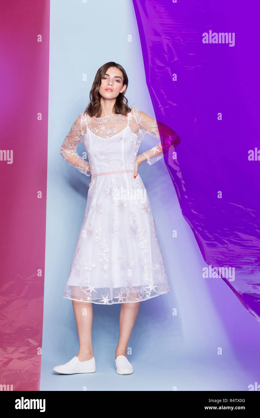 Young female fashion model wearing white dress and posing with colored panels Stock Photo
