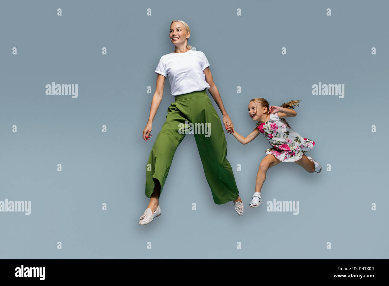 Mother and daughter running on blue background Stock Photo