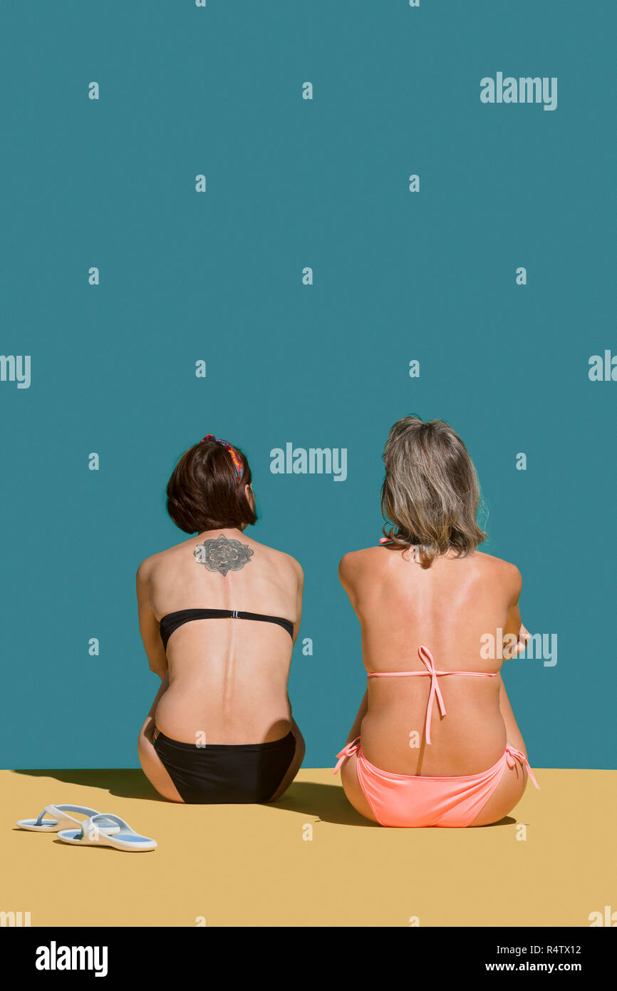 Women in bikinis sunbathing on green background Stock Photo
