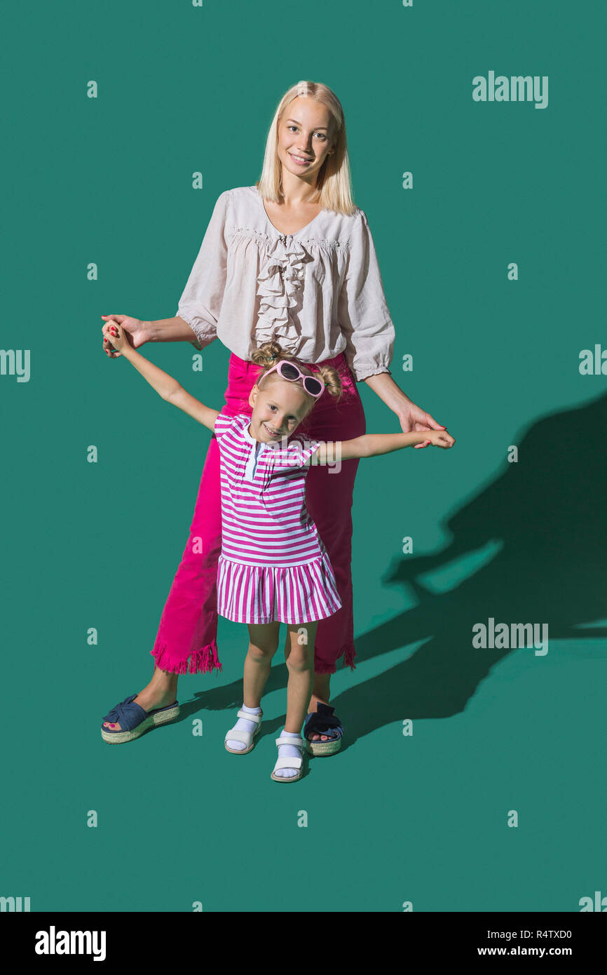 Portrait Mother And Daughter Holding Hands Against Green Background