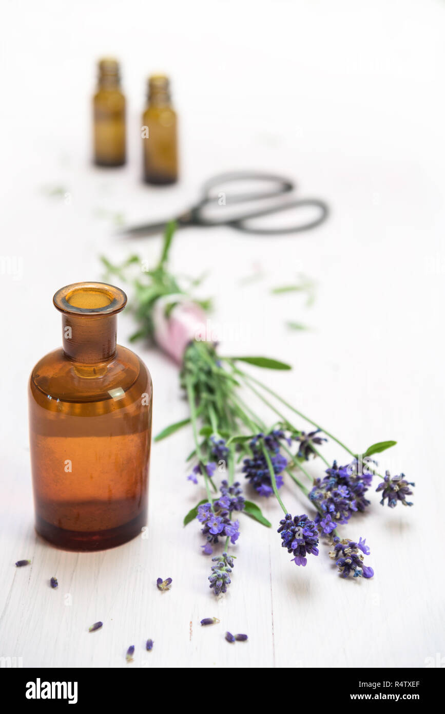 lavender flowers and bottles with essential herbal oil on white painted wood, copy space, vertical, selected focus, very narrow depth of field Stock Photo