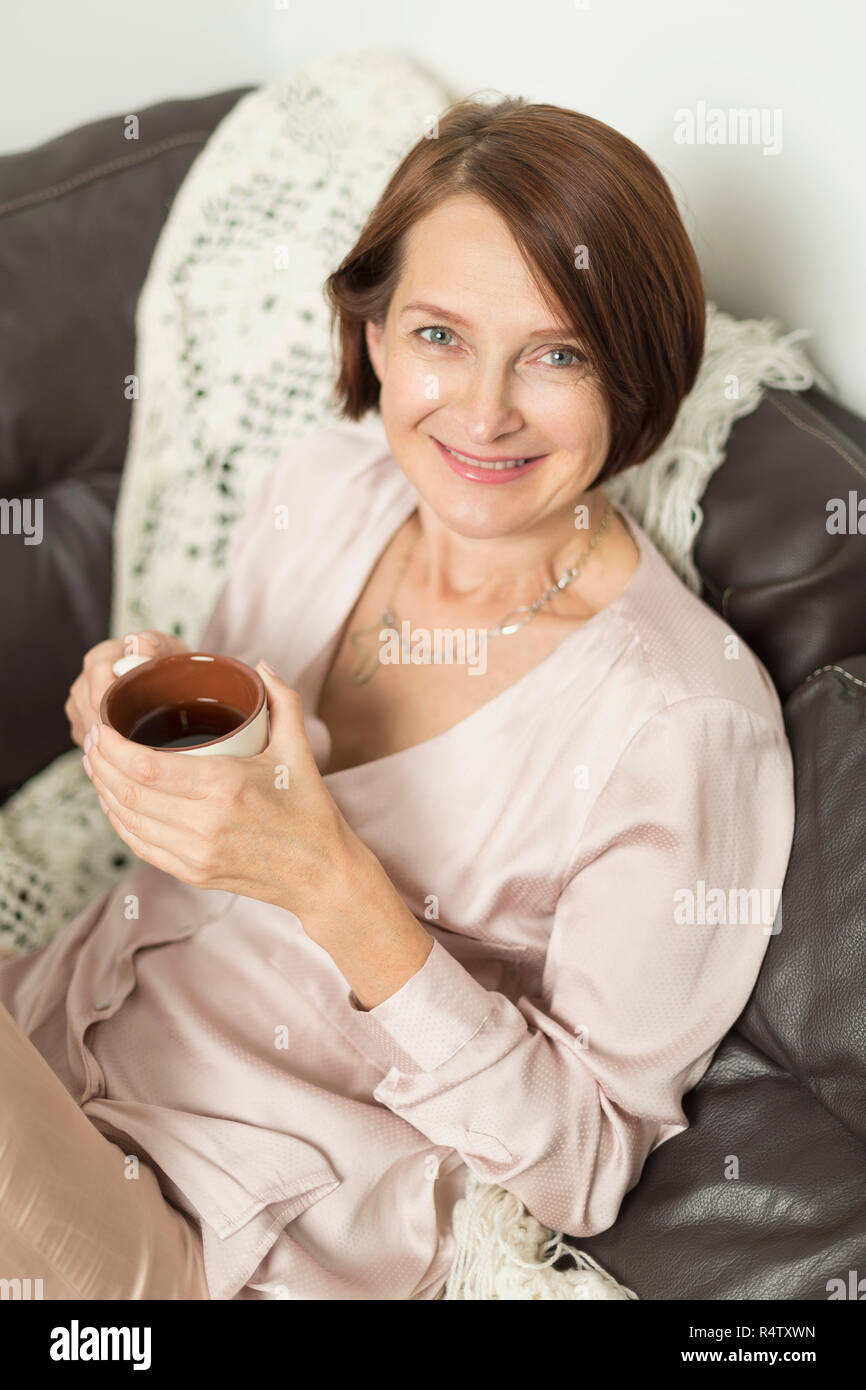 Portrait of mature woman smiling while sitting with hot drink Stock Photo