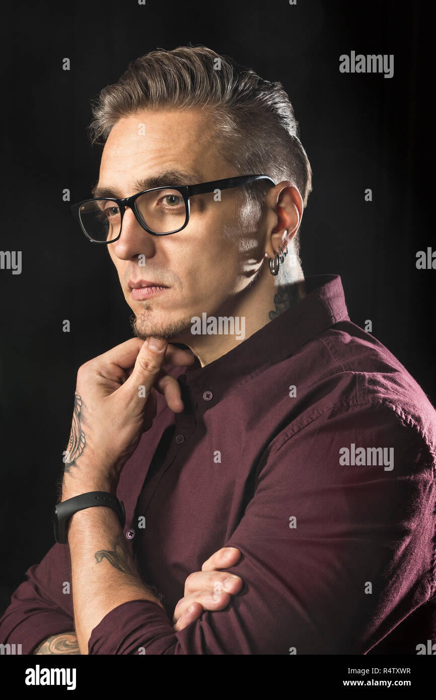 Portrait of serious man wearing glasses and looking away against black background Stock Photo